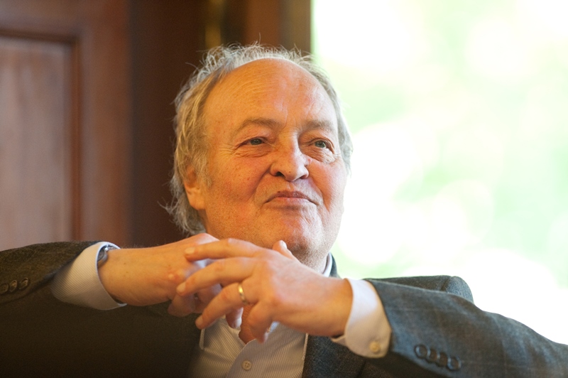 Eine männliche Person gestikuliert und lächelt. Man sieht Kopf, einen Teil des Oberkörpers und Hände.